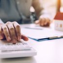 Close up of finger businessman using calculator calculate budget about house contract mortgage in the office room.